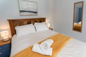 a bedroom with a large white bed with towels on it at Large House in Looe, Near Beach and Bars with Great Views, Free Parking and Free Access to a Nearby Indoor Swimming Pool in Looe