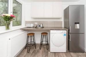 a kitchen with a refrigerator and a counter with stools at Large House in Looe, Near Beach and Bars with Great Views, Free Parking and Free Access to a Nearby Indoor Swimming Pool in Looe