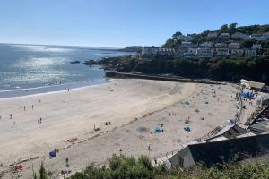 a group of people on a beach near the water at Large House in Looe, Near Beach and Bars with Great Views, Free Parking and Free Access to a Nearby Indoor Swimming Pool in Looe