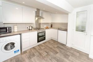 a kitchen with white cabinets and a washer and dryer at Large House in Looe, Near Beach and Bars with Great Views, Free Parking and Free Access to a Nearby Indoor Swimming Pool in Looe