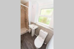 a bathroom with a toilet and a sink and a window at Large House in Looe, Near Beach and Bars with Great Views, Free Parking and Free Access to a Nearby Indoor Swimming Pool in Looe