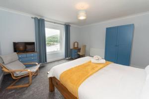 a bedroom with a bed and a chair and a television at Large House in Looe, Near Beach and Bars with Great Views, Free Parking and Free Access to a Nearby Indoor Swimming Pool in Looe