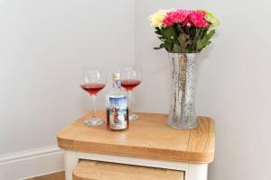 a table with two glasses of wine and a vase of flowers at Large House in Looe, Near Beach and Bars with Great Views, Free Parking and Free Access to a Nearby Indoor Swimming Pool in Looe