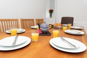 a wooden table with white plates and glasses of orange juice at Large House in Looe, Near Beach and Bars with Great Views, Free Parking and Free Access to a Nearby Indoor Swimming Pool in Looe
