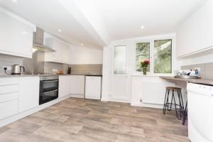 a kitchen with white cabinets and a wooden floor at Large House in Looe, Near Beach and Bars with Great Views, Free Parking and Free Access to a Nearby Indoor Swimming Pool in Looe