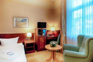 ハルバーシュタットにあるHotel Villa Heine Wellness & Spaのベッド、椅子、テーブルが備わるホテルルームです。