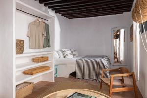 una habitación blanca con una cama y una silla en Eole Tarifa Rooms, en Tarifa