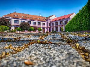 ein großes rosafarbenes Gebäude mit einem Hof mit Blättern auf dem Boden in der Unterkunft U Heligonky in Brünn