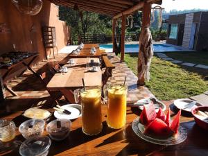 una mesa de madera con copas de zumo y fruta. en Pousada Pato Mergulhão en Vargem Bonita