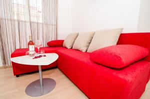 un sofá rojo con una mesa y una botella de vino en Apartment Ira, en Dubrovnik
