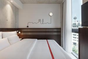 een slaapkamer met een groot wit bed en een raam bij Ruby Ella Hotel Cologne in Keulen