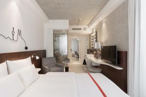a bedroom with a large white bed and a desk at Ruby Ella Hotel Cologne in Cologne