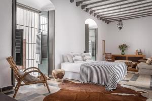 a white bedroom with a bed and a chair at Eole Tarifa Apartments in Tarifa