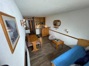 a living room with a blue couch and a kitchen at Le choucas - Les Arcs in Arc 2000