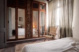 1 dormitorio con cama, silla y espejo en Eole Tarifa Apartments, en Tarifa