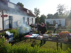 a group of people standing around a table in a yard at STF Vandrarhem Backåkra in Löderup