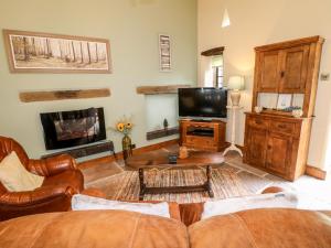 a living room with a couch and a tv at Bluebell Cottage in Alfreton