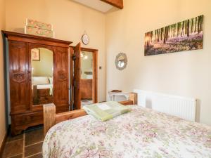 a bedroom with a bed and a wooden cabinet at Bluebell Cottage in Alfreton