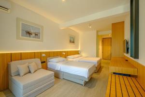 Habitación de hotel con 2 camas y sofá en Dubrave apartmani, en Budva