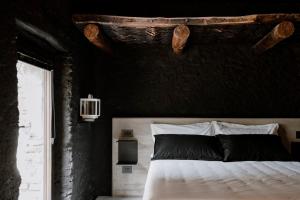 1 dormitorio con 1 cama con pared negra en Lou Estela - L'essiccatoio, en Moiola