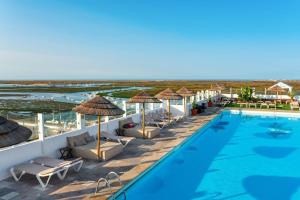 a hotel with a swimming pool and chairs and umbrellas at AP Eva Senses in Faro