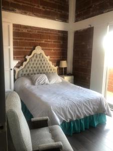 a bedroom with a bed and a chair and a brick wall at Casa Jardin Rosarito in Rosarito