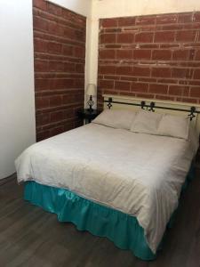 a bed in a room with a brick wall at Casa Jardin Rosarito in Rosarito