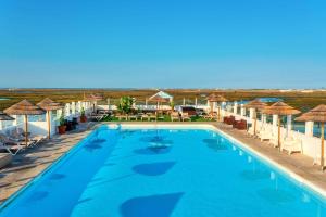 uma piscina num resort com cadeiras e guarda-sóis em AP Eva Senses em Faro