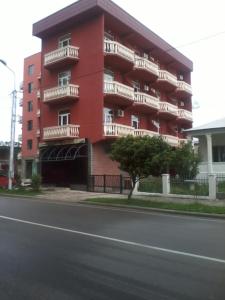 a red building with balconies on the side of a street at guka in Kobuleti