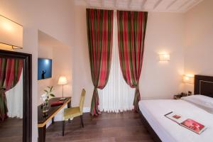 a hotel room with a bed and a desk and curtains at Tridente Suites in Rome