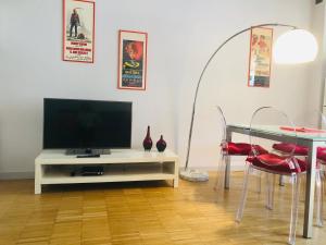 - un salon avec une télévision et une table avec des chaises dans l'établissement Appartamento Porta Susa, à Turin