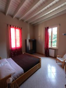 1 dormitorio con 1 cama y 2 ventanas con cortinas rojas en da Irma in terrazza, en Crema