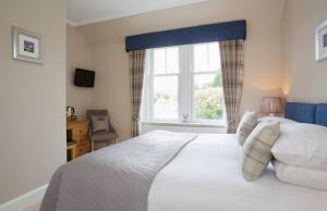 a bedroom with a large white bed with a window at Dunmurray Lodge Guesthouse and Loft Apartment in Pitlochry +51 photos