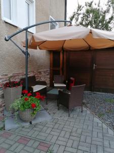 a large umbrella on a patio with chairs and flowers at Barnabáš Rusnák Ubytovanie v súkromí in Mučín