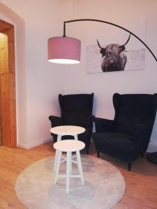 ein Zimmer mit zwei Stühlen, einem Tisch und einem Stier an der Wand in der Unterkunft Ferienwohnung "Kleiner OTTO" in Erfurt