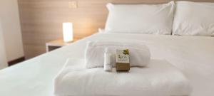 ein weißes Bett mit einem Thermometer und einem Buch darauf in der Unterkunft Hotel Ammare in Sottomarina
