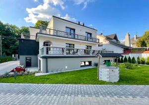 a white house with a balcony and a yard at Bema Rooms in Łódź