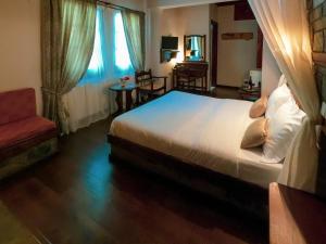 a bedroom with a large bed and a red chair at Amalthia Traditional Guesthouse in Tsagarada