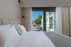 a bedroom with a white bed and a balcony at ALPE LUXURY ACCOMMODATION Penelope Collection in Olympiada +61 photos