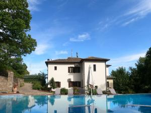 a villa with a swimming pool in front of a house at Amalthia Traditional Guesthouse in Tsagarada