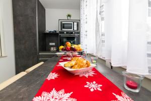 einen Tisch mit einer Schüssel Essen auf einer roten Decke in der Unterkunft APARTMENT NEVERA in Rijeka