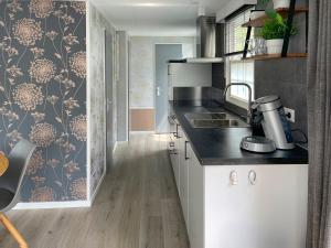 eine Küche mit weißen Schränken und einer schwarzen Arbeitsplatte in der Unterkunft Chalet Natuurrijk in Oisterwijk