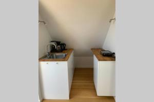 una pequeña cocina con armarios blancos y fregadero en Tag lejlighed i hyggelig landsby på Stevns en Store Heddinge