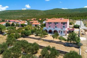 a large pink house in a village with trees at Sonja Vacation home in Podorjak