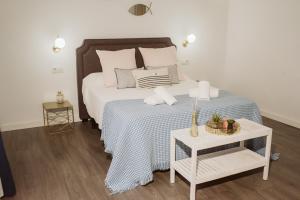a bed with a blue and white bedspread and a table at Apartamento Circo Romano- con vistas al Circo Petfriendly in Merida