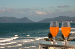 two glasses of beer sitting on a table on the beach at Joaquina Beach Hotel in Florianópolis
