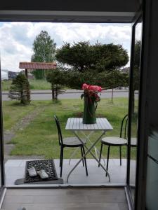 a table and chairs with a vase of flowers on a porch at Pokoj hotelowy bis dwu osobowy in Łeba