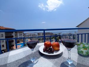 two glasses of wine on a table with apples and grapes at Vega Village Ap A8 in Sveti Vlas