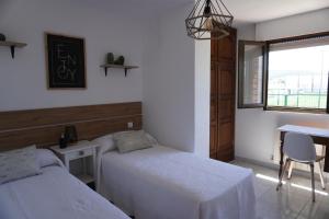 sypialnia z dwoma łóżkami, stołem i oknem w obiekcie Hostal La Biela 43 w mieście Galizano