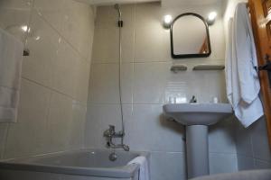łazienka z umywalką, wanną i lustrem w obiekcie Hostal La Biela 43 w mieście Galizano